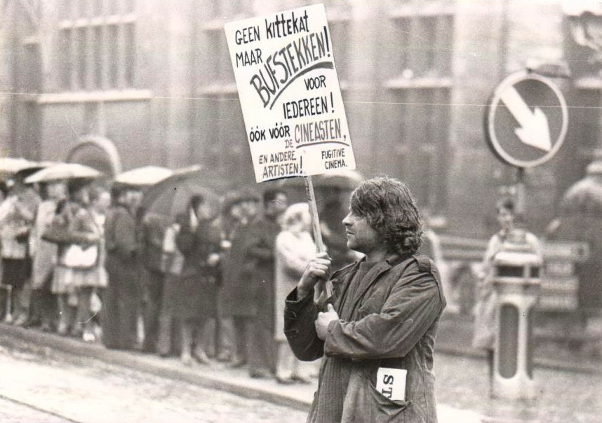 (1) Robbe De Hert tijdens een protestactie tegen het filmbeleid in 1974: ‘Geen kittekat maar bufstekken! Voor iedereen! Óók vóór de cineasten en andere artiesten!’ Bron: Fugitive Cinema Archief.